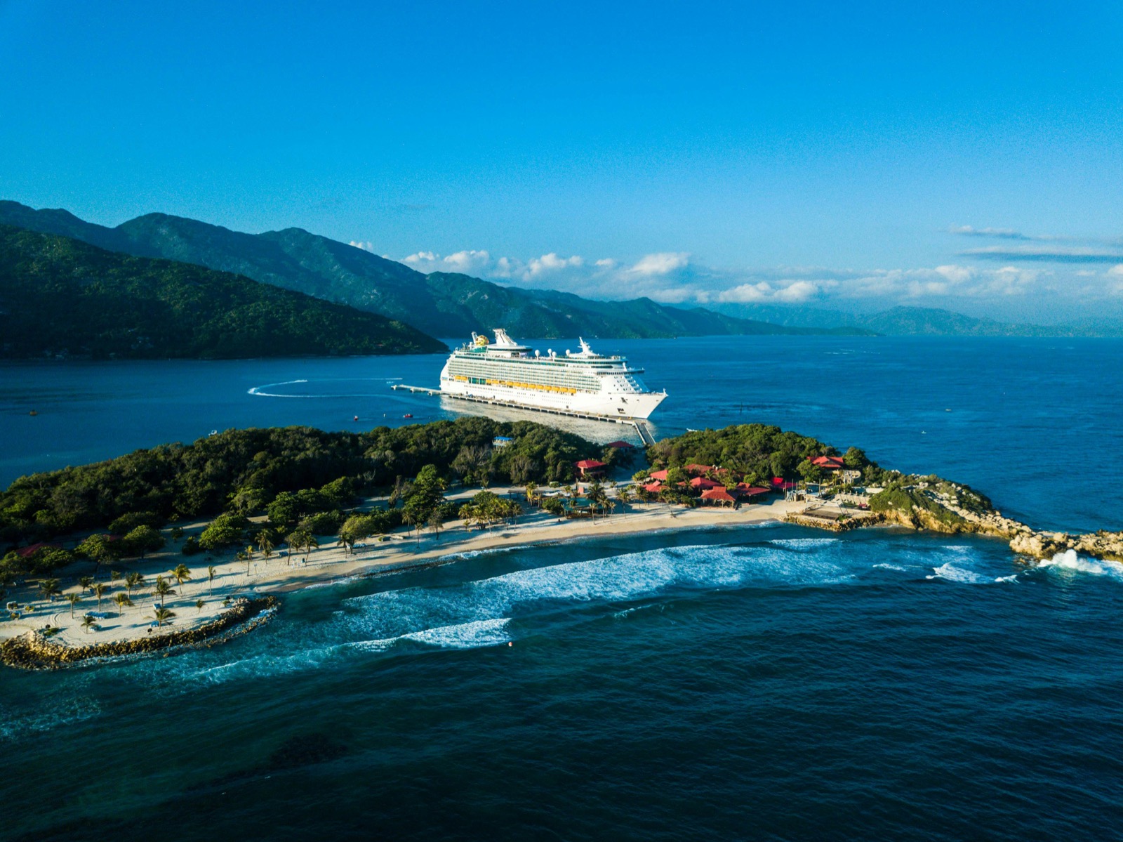Aerial view of a cruise ship docked at a tropical Caribbean island with turquoise water